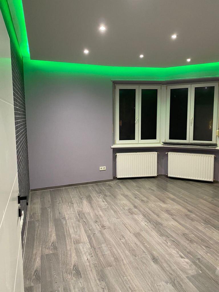 Salon après rénovation par BATI-LUX : faux plafond avec spots et éclairage LED indirect, sol stratifié, peinture neuve