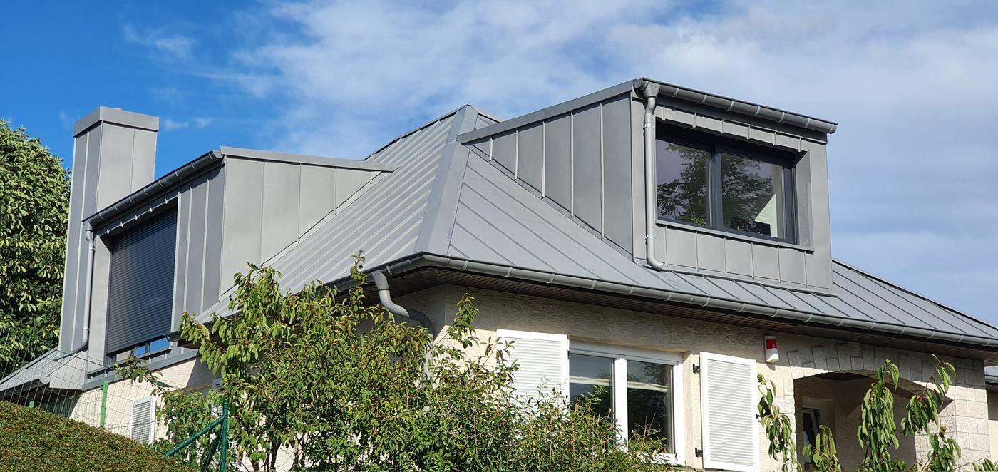 Maison après travaux BATI-LUX : toiture en zinc à joints debout, deux grandes lucarnes et cheminée habillée