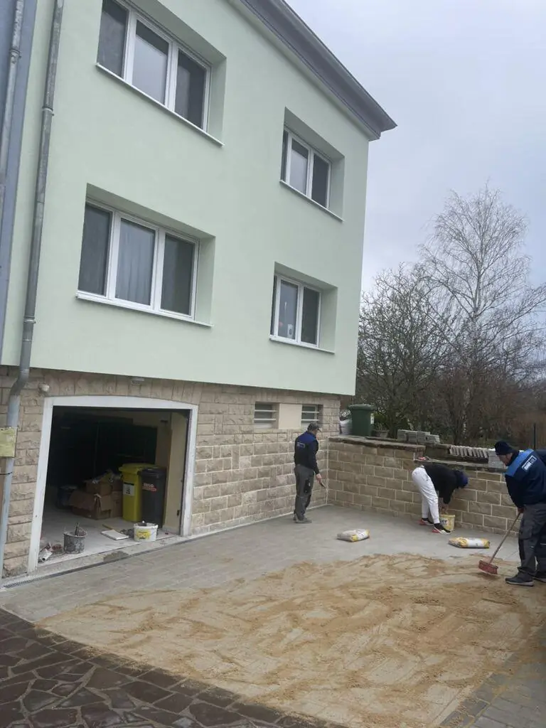 Maison avec nouvelle façade vert clair, garage et cour pavée terminés