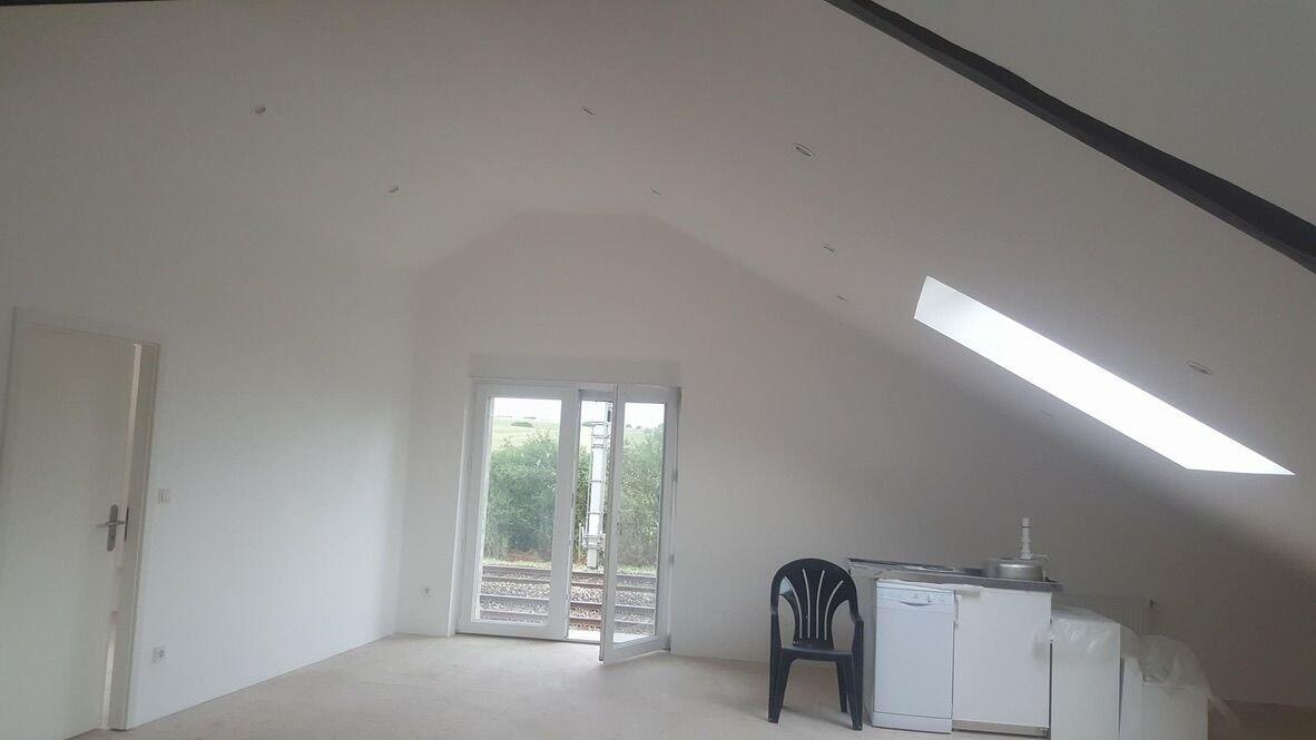 Après : grenier transformé en pièce de vie lumineuse par BATI-LUX, avec porte-fenêtre et velux